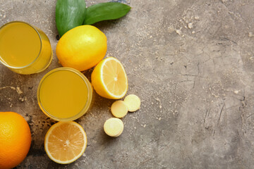 Glasses of vitamin C effervescent tablet dissolved in water and fruits on grey grunge table
