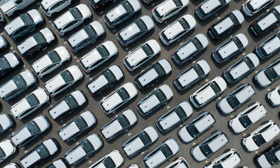 Aerial view of new cars stock at factory parking lot. Above view cars parked in a row. Automotive...