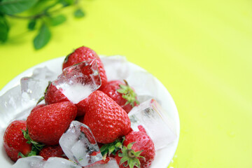 Ice drink concept with fresh strawberries and green leaves background
