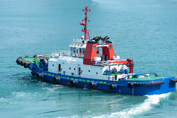 Tug boat in the container terminal, she is about to assist to a big container ship during maneuvering operations.