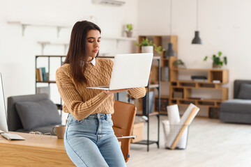Young female programmer with laptop in office