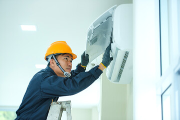 An Asian young Technician service man wearing blue uniform checking,Professional air conditioner installer maintaining modern indoor air conditioner space for text