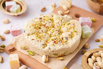 Wooden board of tasty Tahini halva with pistachios on light background