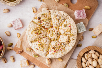 Wooden board of tasty Tahini halva with pistachios on light background