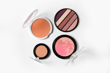 Eyeshadows, blush and makeup powder on light background