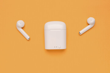 Modern white earphones on beige background