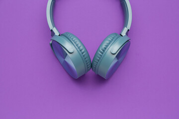 Modern blue headphones on purple background