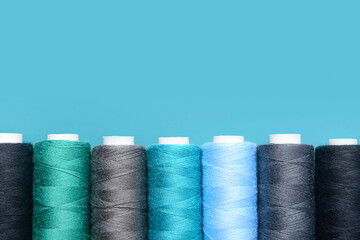 Set of different thread spools on blue background, closeup