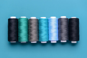 Set of different thread spools on blue background