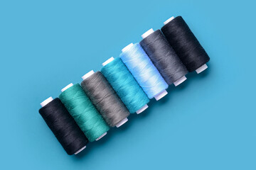Set of different thread spools on blue background