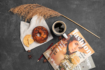 Cup of coffee with pastry, magazine and pampas grass on dark background