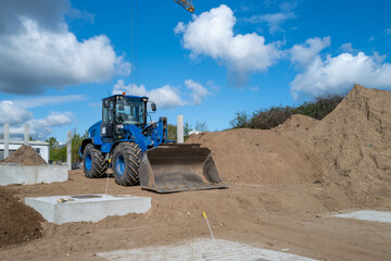 a blue wheel loader stands on a construction site