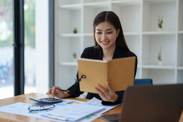 Young asian female work with financial papers at home count on calculator before paying taxes receipts online, planning budget glad to find chance for economy saving money, audit concepts