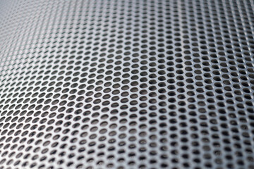 A seemingly endless pattern of circles fades away into the distance on a steel panel that has been precision etched, making a secure grate for an enclosure.