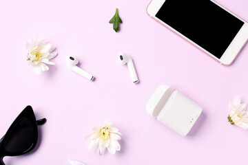Composition with modern earphones, case, mobile phone, sunglasses and flowers on color background