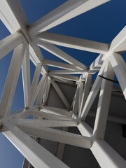 The geometric design of a steel tower, looking up into and through the criss-crossing metal structure.