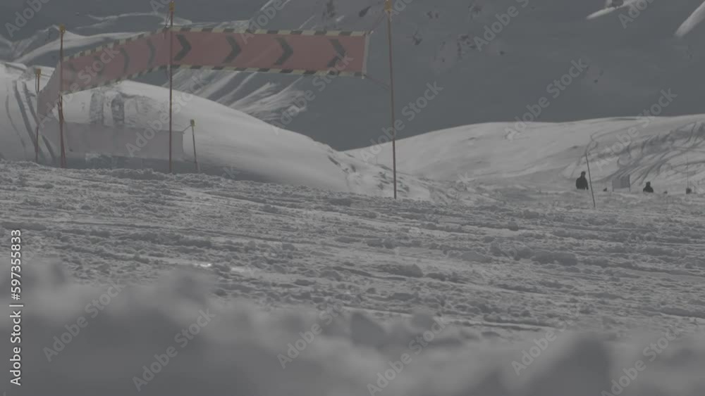 Poster slowmotion shot of a skier passing by on the slopes with orange warning signs in the background on a