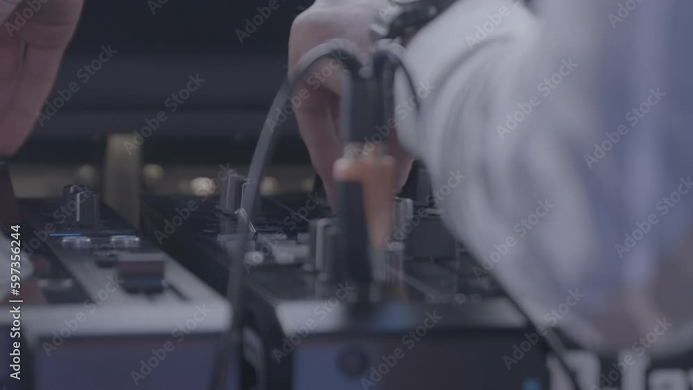 Poster dj playing a set while touching the buttons on his mixing panel in slowmotion log