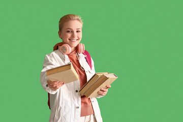 Female student with books on green background