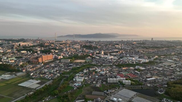 Aerial view of sprawling coastal city with suspension bridge to island at sunset