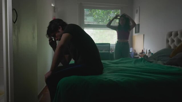 Intense Couple Conflict: Man Under Pressure from Partner While Woman Discusses Relationship in Background, Leaving Him Depressed and Frustrated