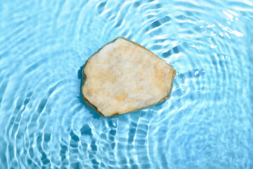 Flat stone in water on blue background