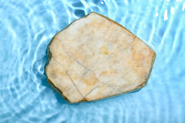 Flat stone in water on blue background