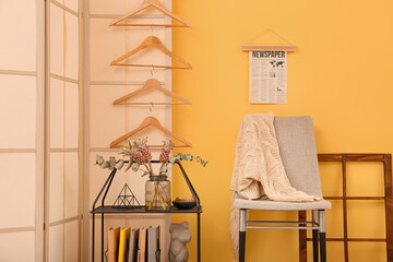 Interior of stylish room with shelving unit, chair and folding screen