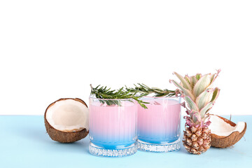 Glasses of cocktail with rosemary, coconut and baby pineapple on table near white wall