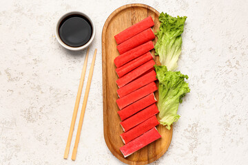 Wooden board with tasty crab sticks and sauce on light background © Pixel-Shot