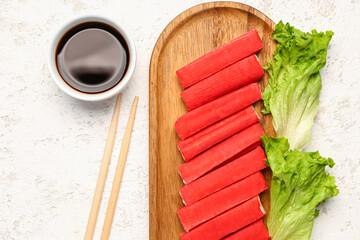 Wooden board with tasty crab sticks and sauce on light background, closeup © Pixel-Shot