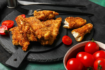 Boards of tasty fried codfish on green background