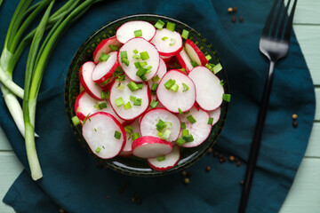 Bowl with slices of fresh radish on wooden table