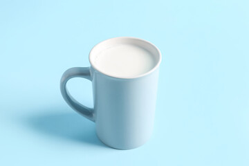 Cup with fresh milk on blue background