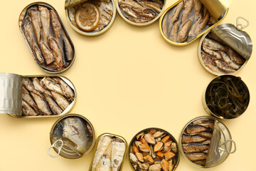 Frame made of tin cans with different seafood on beige background
