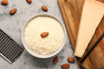 Bowl with tasty Parmesan cheese on grunge background