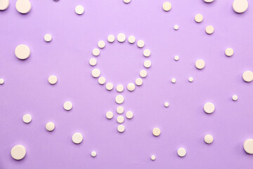 Symbol of woman made with hormonal pills on lilac background