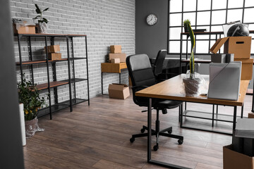 Workplaces with cardboard boxes in office on moving day