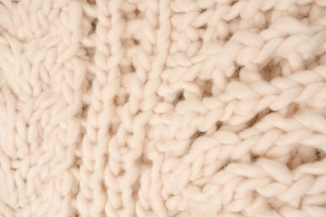 A fragment of beige knitted fabric, knitted from white sheep wool.