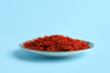 Plate with pile of saffron on blue background