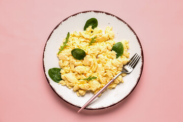 Plate of delicious scrambled eggs with herbs on pink background