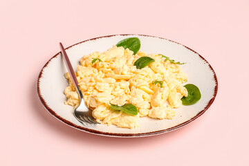 Plate of delicious scrambled eggs with herbs on pink background
