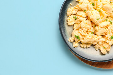 Plate of scrambled eggs with herbs on light blue background