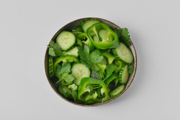 Bowl of salad with green vegetables on grey background