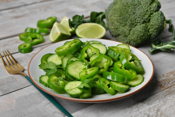 Plate of salad with green vegetables on grey wooden background