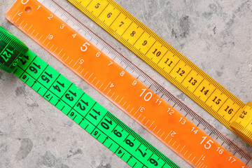 Colorful measuring tapes and plastic ruler on grey grunge background