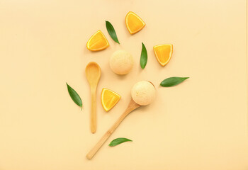 Bath bombs with orange slices, wooden spoons and leaves on beige background
