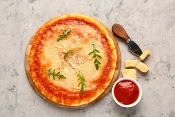 Wooden board of tasty pizza with parmesan cheese and tomato sauce on grey grunge background