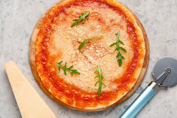 Wooden board of tasty pizza with parmesan cheese and cutter on grey grunge background