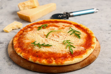 Wooden board of tasty pizza with parmesan cheese and cutter on grey grunge background